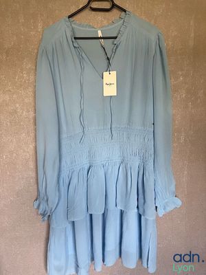 the blue dress is hanging on a hanger on the wall
