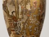 a gold vase with a painting on it on a table