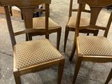 four wooden chairs with woven seats in a store