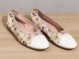 pair of white shoes with a floral design on them on a wooden surface