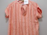 an orange shirt hanging on a hanger on a wall