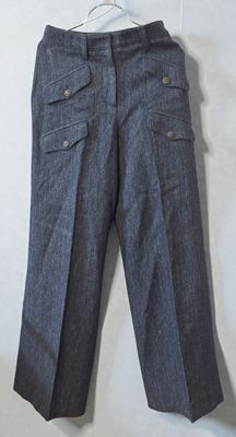 grey pants hanging on a hanger on a white wall