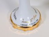 a white vase with a gold rim on a white table
