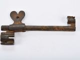an old rusty key on a white surface with a hole in the middle