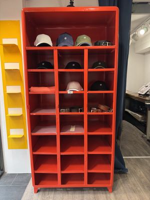 une bibliothèque rouge sur laquelle sont posés tout un tas de chapeaux
