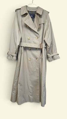 trench coat hanging on a hanger on a white wall