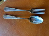 two silver spoons and a fork on a brown table