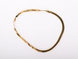 a close up of a gold necklace on a white surface