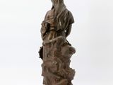 bronze statue of a woman sitting on a rock with her hands in her pockets