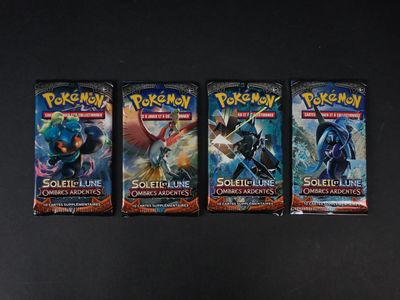 trois paquets de cartes à collectionner Pokémon posés sur une surface noire