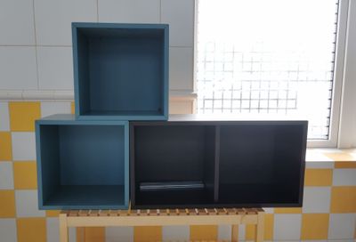 a blue and yellow shelf in a bathroom next to a window