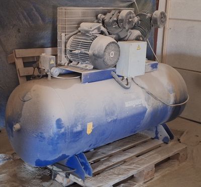 un gros compresseur d'air posé sur une palette dans un garage