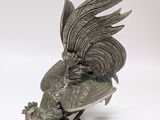 a silver statue of a rooster on a white surface