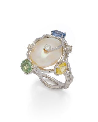 un gros plan d'une bague ornée d'une perle et de pierres multicolores