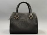 a black handbag with a braid handle on a white background