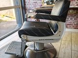 un fauteuil de coiffeur noir et blanc devant un mur de briques