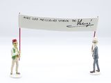 two figurines of a man holding a sign and a flag