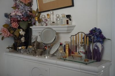 une commode avec un miroir et de nombreux flacons de parfum posés dessus