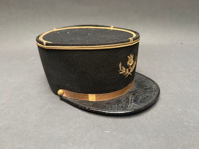 un chapeau noir orné d'une bordure dorée, posé sur une surface grise