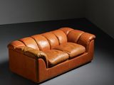 an image of a brown leather couch sitting in a dark room