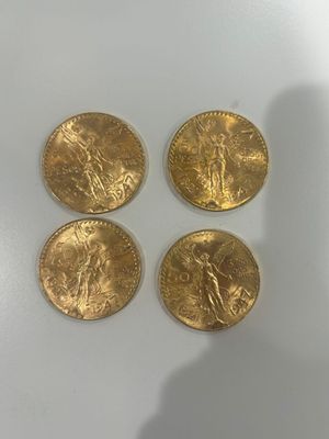 quatre pièces d'or posées sur une table, à côté d'une personne