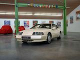 une voiture blanche garée dans un garage, avec d'autres voitures en arrière-plan