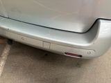 the rear end of a silver car with a red sticker on it ' s bumper