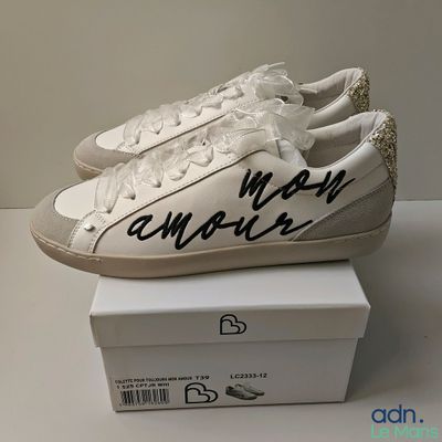 white sneakers with black lettering on them sitting on top of a box