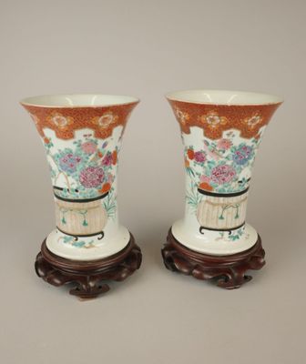 une paire de vases chinois ornés de fleurs, posés sur des socles, sur un fond gris