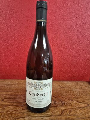 une bouteille de vin posée sur une table devant un mur rouge