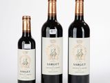 trois bouteilles de vin posées les unes à côté des autres sur une surface blanche