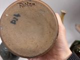 a person holding a brown vase with writing on it