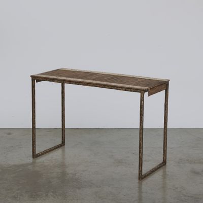 La table est en bois et possède un piètement en métal.