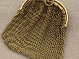 a gold metal purse with a chain around it