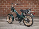 a small green motorcycle parked in front of a brick wall