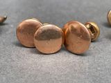 three pairs of copper stud earrings on a gray surface