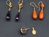 trois paires de boucles d'oreilles et une broche posées sur un fond noir