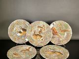 four plates with birds and flowers on them sitting on a table