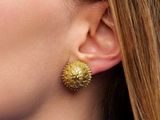 a close up of a woman wearing a blue shirt and gold earrings