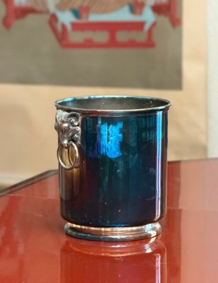 a blue glass cup with a silver handle on a table