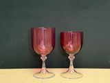 two wine glasses sitting on a table with a green wall in the background