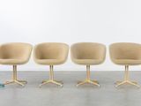 four beige chairs sitting on top of each other in front of a white wall