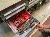 un homme en train d'ouvrir un tiroir contenant des outils