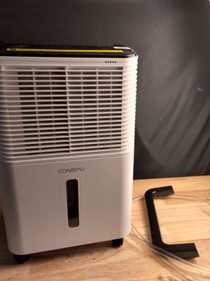 un climatiseur posé sur une table en bois, à côté d'un téléphone