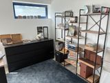 une pièce équipée d'un bureau, d'étagères et d'une commode