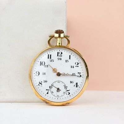 une montre de poche en or posée sur un bloc de marbre