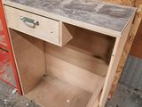 a wooden desk with a drawer underneath it in a garage