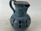un vase bleu avec une anse noire sur un fond blanc
