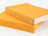 two yellow books stacked on top of each other on a white surface