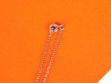 a close up of a necklace on an orange piece of paper